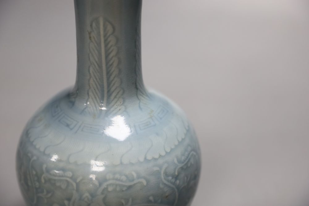 A Chinese bottle vase with carved detail under a pale blue glaze, height 22cm